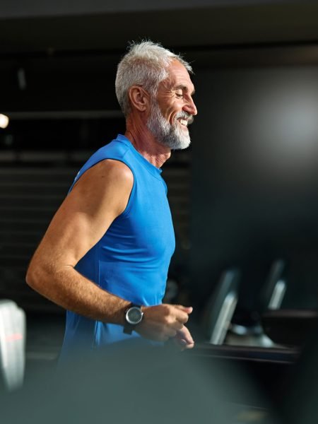 Portrait of a senior man exercising in a gym, mature male running using treadmill machine equipment, healthy lifestyle and cardio exercise at fitness club concepts, vitality and active senior, coach training